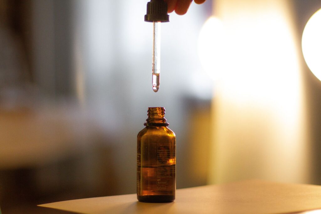 amber glass dropper bottle with a pipette dispensing a single drop