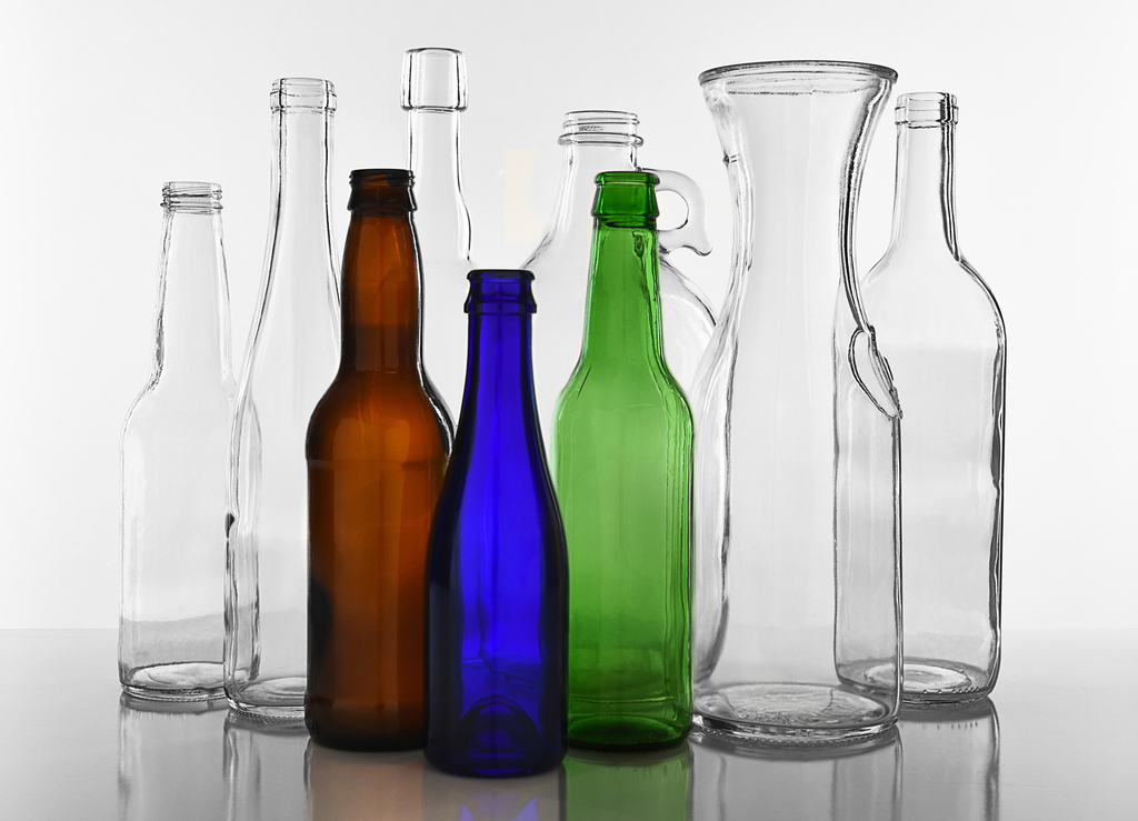 assorted clear, amber, blue, and green glass bottles in various shapes and sizes